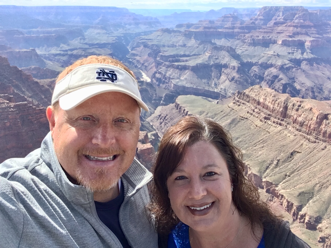 Couple smiling in front of Grand Canyon.