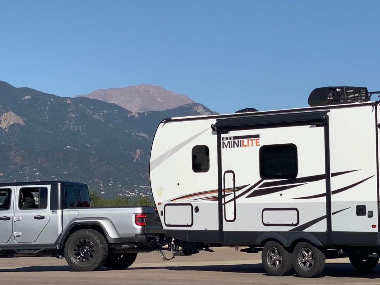 Close up of Jeep Gladiator towing RV in front of Pikes Peak.